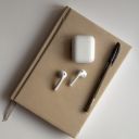 AirPods 2 Resting on a Notebook Beside a Pen  screen for extension Chrome web store in OffiDocs Chromium