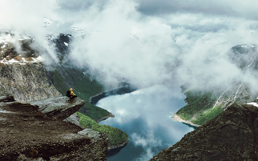A man sits at the edge of Trolltunga  from Chrome web store to be run with OffiDocs Chromium online