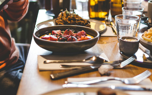 A Person Taking a Picture of Food on a Dining Table  from Chrome web store to be run with OffiDocs Chromium online