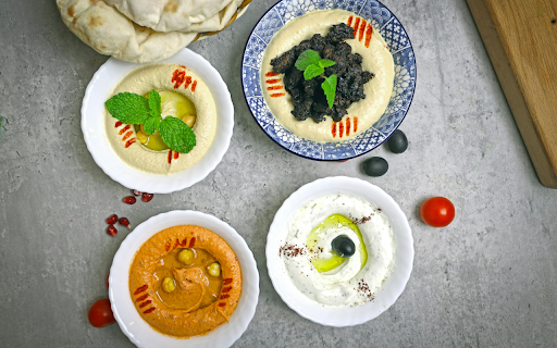 A table with four bowls of hummus and a bowl of olives  from Chrome web store to be run with OffiDocs Chromium online