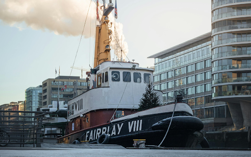 A tug boat is parked in front of a building  from Chrome web store to be run with OffiDocs Chromium online