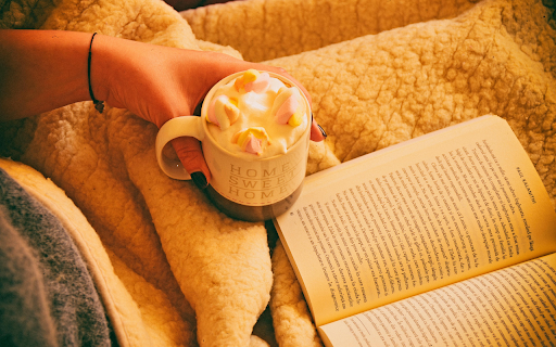 Person Holding Mug Filled With Pastry Beside Open book  from Chrome web store to be run with OffiDocs Chromium online