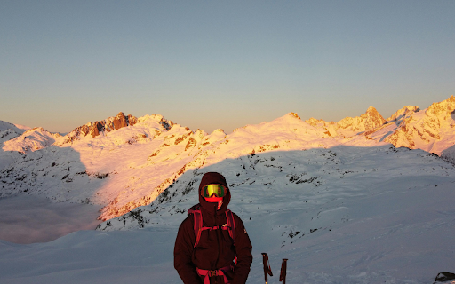 Person in Jacket and Goggles in Mountains at Sunset  from Chrome web store to be run with OffiDocs Chromium online