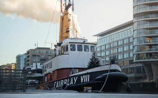 A tug boat is parked in front of a building  from Chrome web store to be run with OffiDocs Chromium online