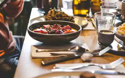 A Person Taking a Picture of Food on a Dining Table  from Chrome web store to be run with OffiDocs Chromium online